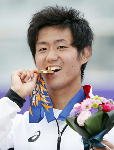 男子シングルスで優勝し、笑顔で金メダルをかむ西岡良仁