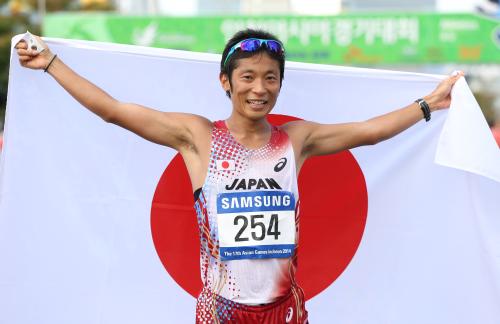 男子５０キロ競歩で金メダルを獲得し、日の丸を掲げる谷井