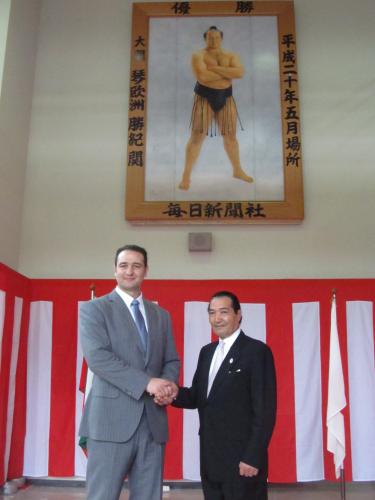 贈呈した優勝額の前で松浪健四郎日体大理事長と握手をする琴欧洲親方（左）