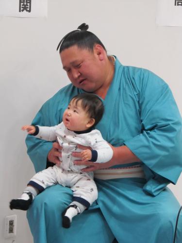 スポニチプラザでのトークショー後にファンの赤ちゃんを抱く旭天鵬