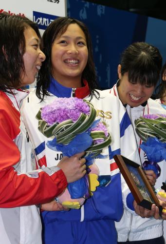 女子５０メートル平泳ぎ決勝で優勝した渡部香生子（中央）は表彰式で笑顔を見せる