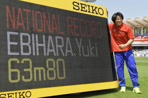 女子やり投げで63メートル80の日本新記録をマークし、電光掲示板の前で笑顔の海老原有希