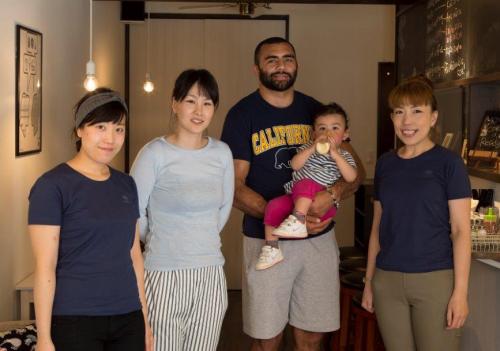 今月１日に府中市美好町にオープンしたカフェ「Ｃａｆｅ＋６４」で記念撮影したラグビー日本代表のリーチ・マイケル（右から２人目）、長女の真依ちゃん、知美夫人（右から３人目）とスタッフ