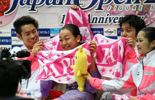 ＜ジャパンオープン２０１５＞演技を終えた浅田真央は村上大介（左）、宇野昌磨（右から２人目）と「ＪＡＰＡＮ］タオルをかざして笑顔。右は宮原知子