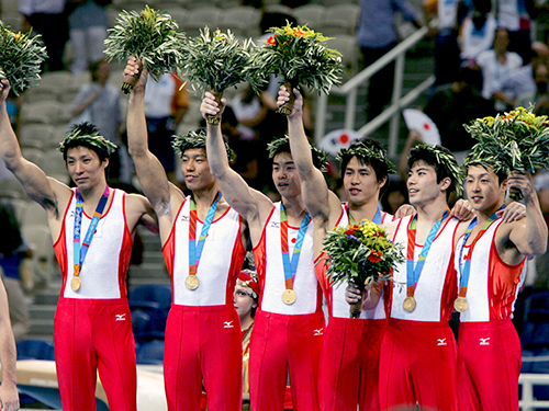 アテネ五輪体操男子団体で金メダルを獲得し、表彰台で喜ぶ（左から）米田）、水鳥、鹿島、冨田、塚原、中野