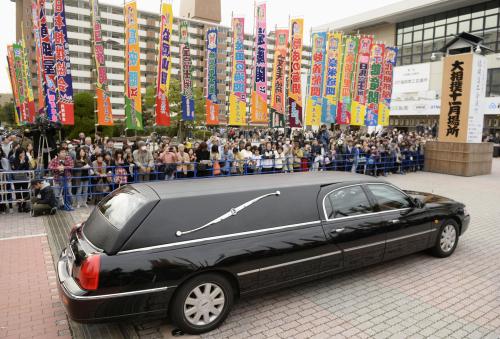 大相撲九州場所の会場に集まった大勢のファンに見送られる、北の湖理事長の遺体を乗せた車＝21日午後、福岡市の福岡国際センター