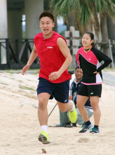 バドミントンの日本代表合宿で、砂浜を走る桃田賢斗。右は奥原希望