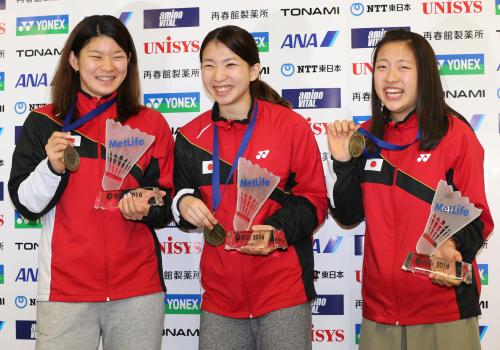 帰国しメダルとトロフィーを手に笑顔を見せる（左から）高橋、松友、奥原