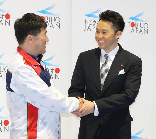 平井委員長（左）と笑顔で握手を交わす北島