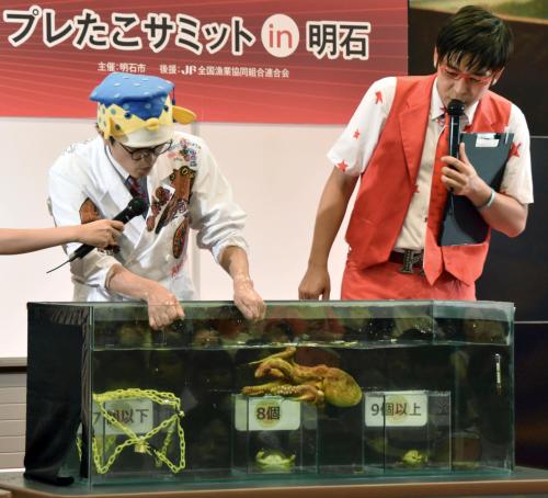 リオ五輪で日本代表が獲得する金メダル数を「８個」と占ったタコ。左は明石たこ大使のタレント「さかなクン」＝