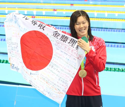 ２００ｍ平泳ぎで金メダルを獲得した金藤はメッセージの書かれた日の丸を掲げる