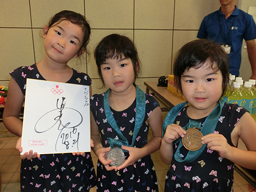 中村真衣さんがシドニー五輪で獲得銀、銅メダルとサイン色紙を手にする根石咲良さん（左）と双子姉妹
