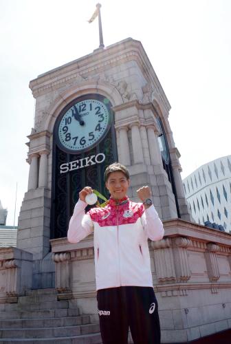 銀座・和光屋上の時計塔前で銀メダルを手にガッツポーズを見せる山県（提供写真）