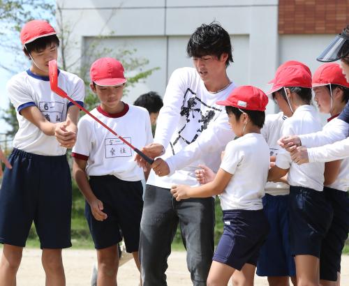 小学校を訪問、子供たちにクラブの握りを教える石川