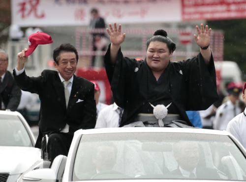 優勝祝賀パレードで多くの観客の手を振る豪栄道（左は北川法夫市長）