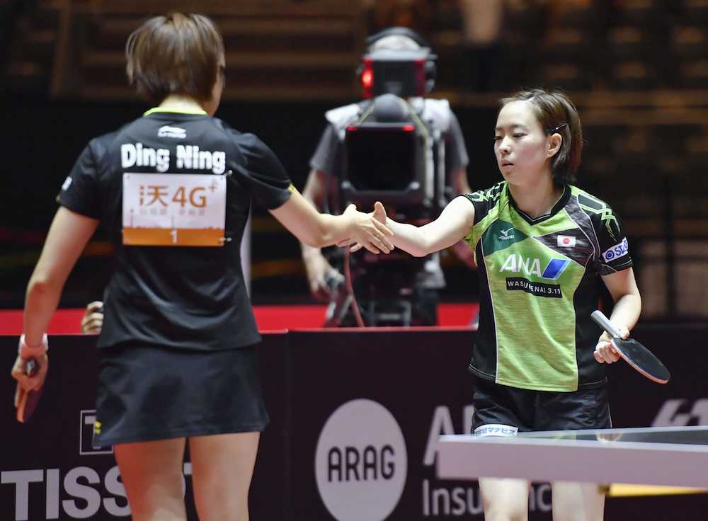 女子シングルス準々決勝で敗退し、丁寧（左）と握手する石川