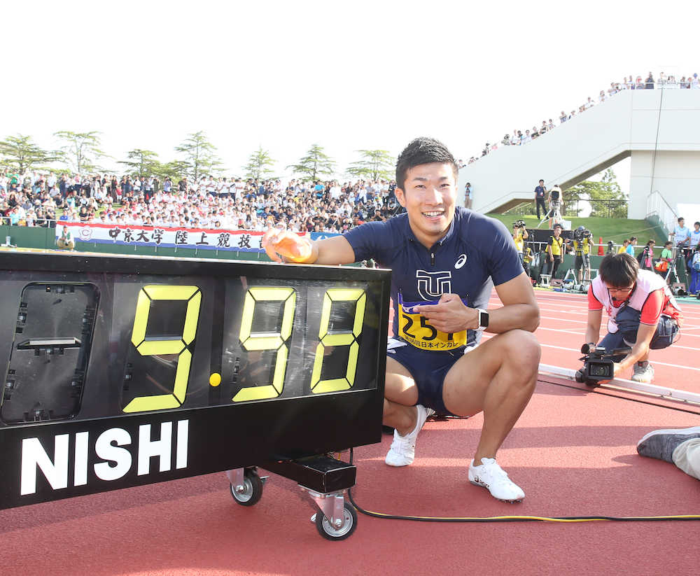 日本人初の９秒台となる９秒９８をマークし、タイムが表示された電光掲示板とともに笑顔の桐生