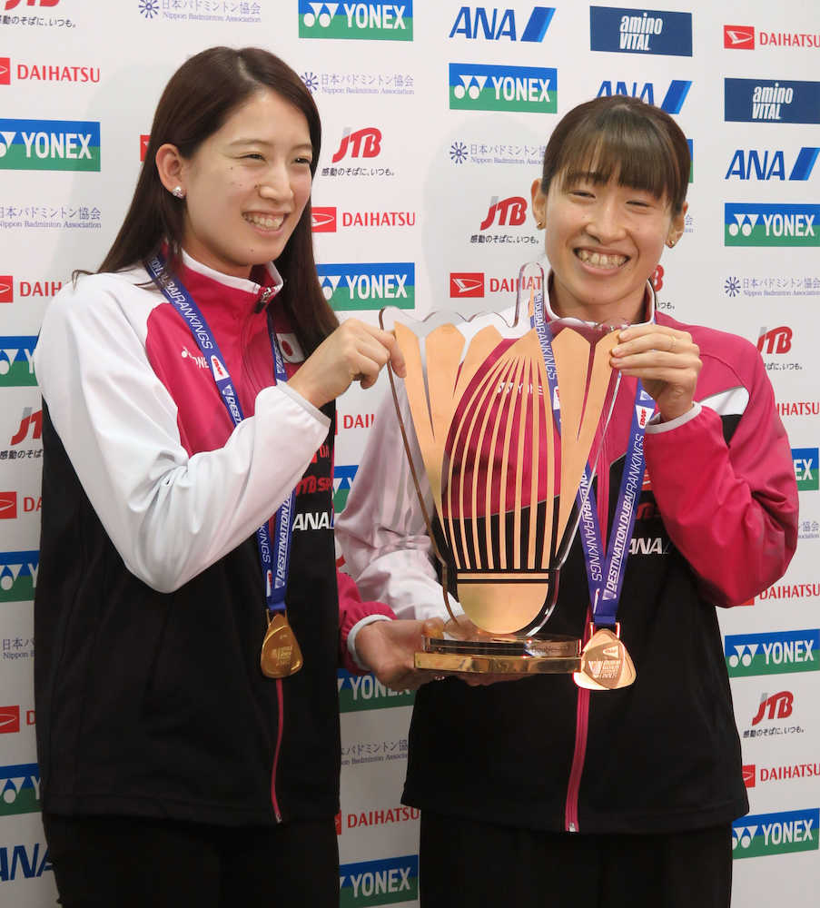 帰国後、バドミントンのＳＳファイナルの金メダルとトロフィーを掲げる女子ダブルスの米元（左）と田中組