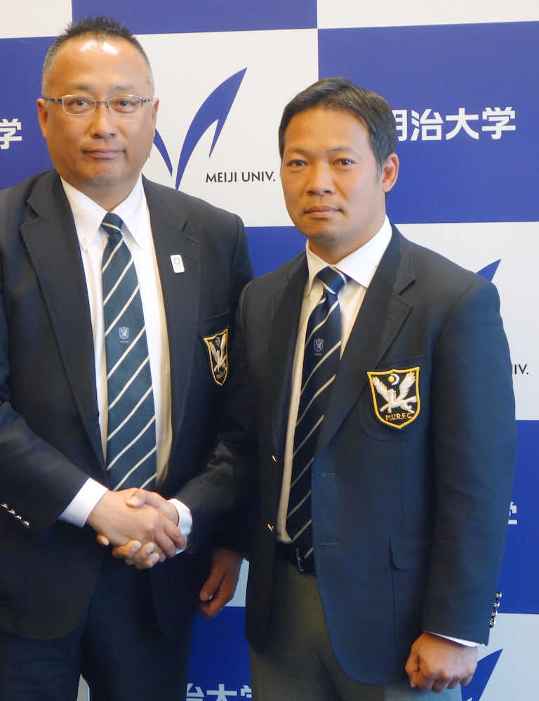 就任記者会見で握手する明大ラグビー部の田中新監督（右）と丹羽前監督