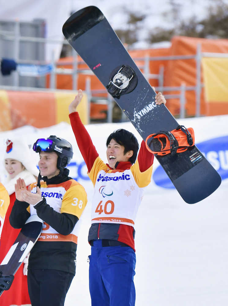 スノーボードクロス男子下肢障害で銅メダルを獲得し、ボードを掲げて大喜びの成田緑夢