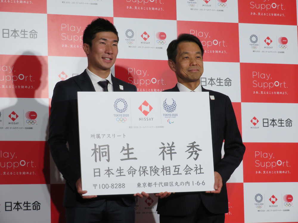 特大サイズの名刺を手に記念撮影に応じる桐生（左）と清水社長