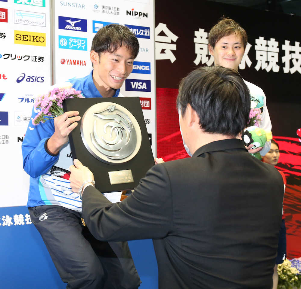 鈴木大地スポーツ庁長官（右手前）から盾をもらい笑顔の入江