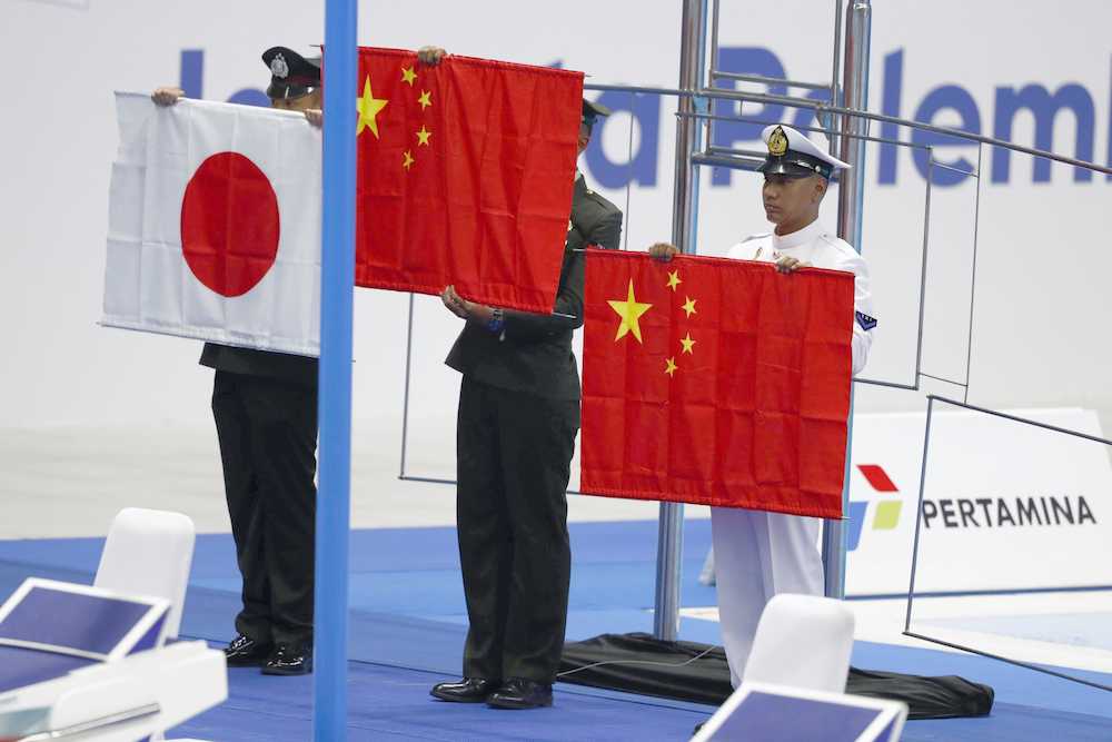 競泳男子２００メートル自由形の表彰式で、掲揚中に落下した中国国旗と日の丸を持つ関係者