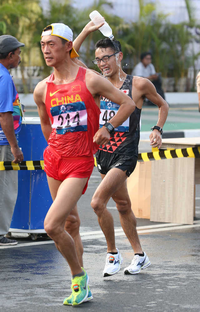 ＜アジア大会陸上＞男子２０キロ競歩、水を頭からかぶりながら王凱華（左）を懸命に追う山西利和（撮影・小海途　良幹）