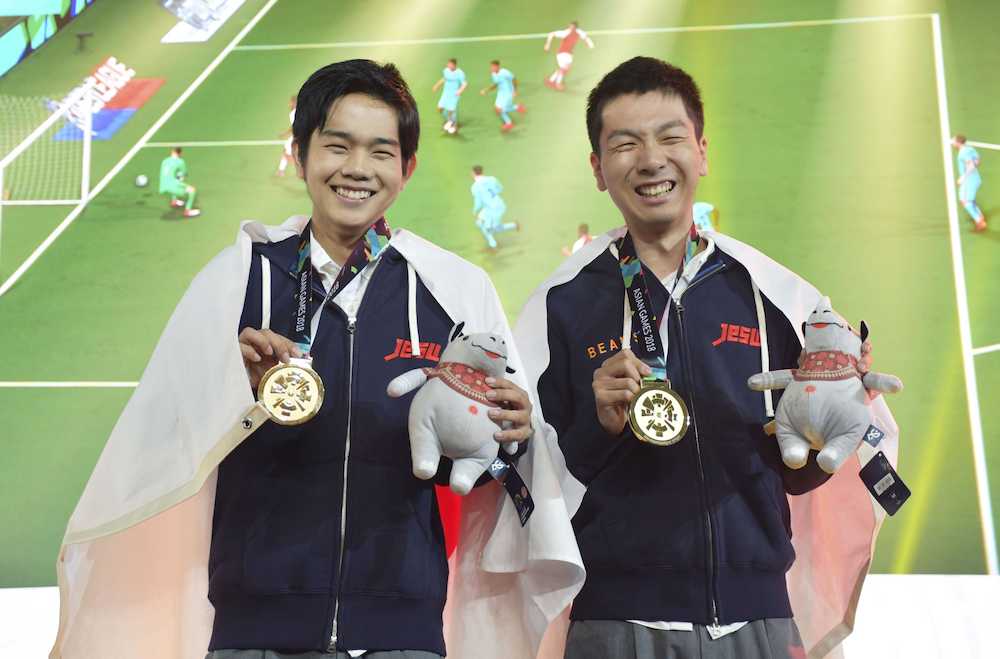 ジャカルタ・アジア大会の公開競技「ｅスポーツ」の人気サッカーゲーム「ウイニングイレブン」で優勝し、笑顔で金メダルを手にする杉村（右）と相原
