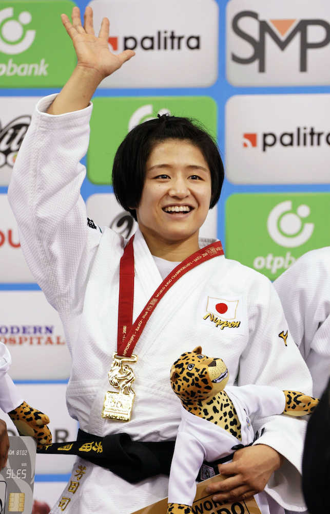 柔道世界選手権女子５７キロ級で獲得した金メダルを胸に笑顔で手を振る芳田