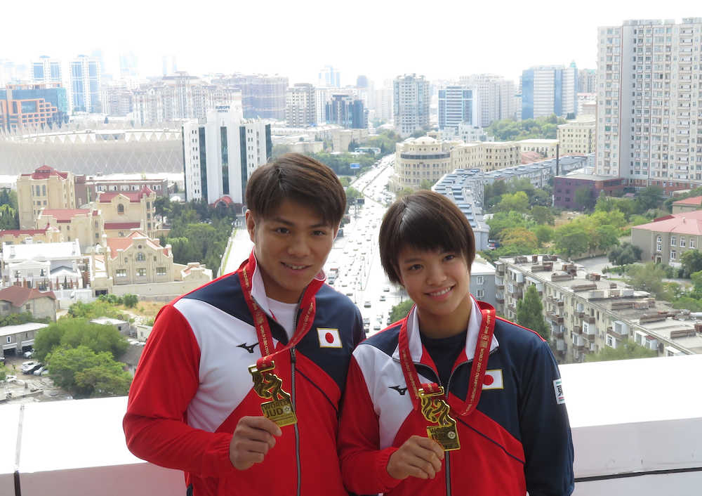 柔道世界選手権で兄妹で金メダルを獲得した阿部一二三（左）、詩の兄妹はアゼルバイジャンのバグーの街並みを背に笑顔