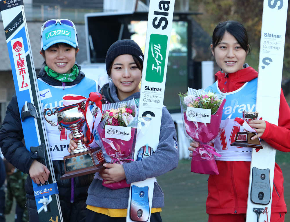 優勝した高梨（中央）は表彰台で笑顔。左は２位・伊藤、右は３位・丸山