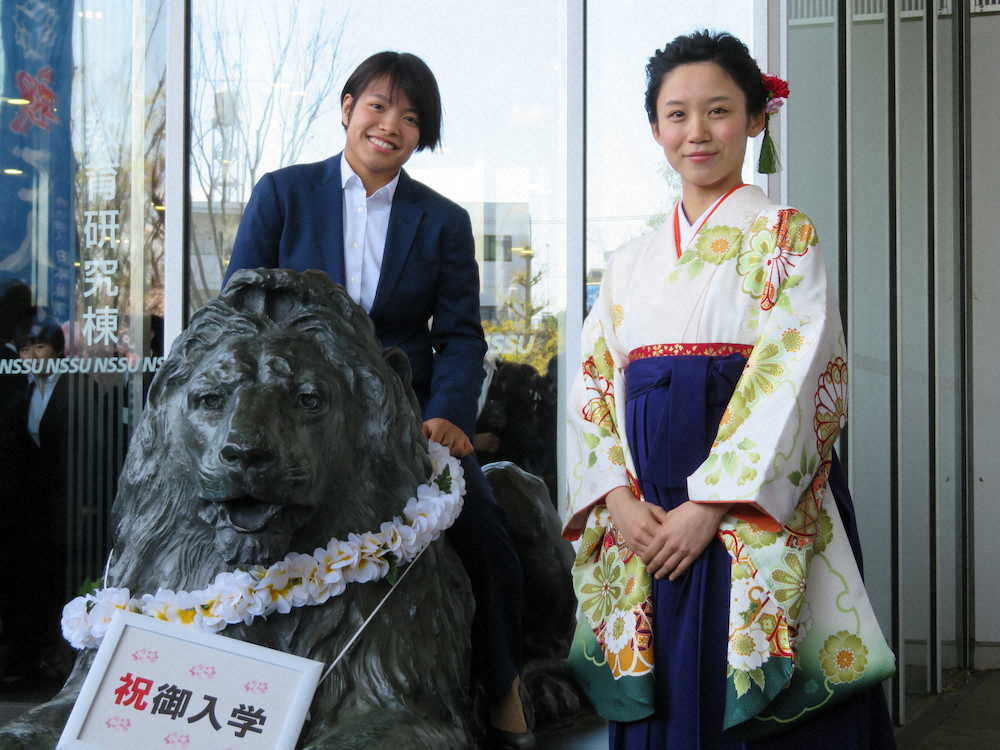 入学式を終え、ライオン像の上に乗って笑顔の阿部詩（左）と高木美帆
