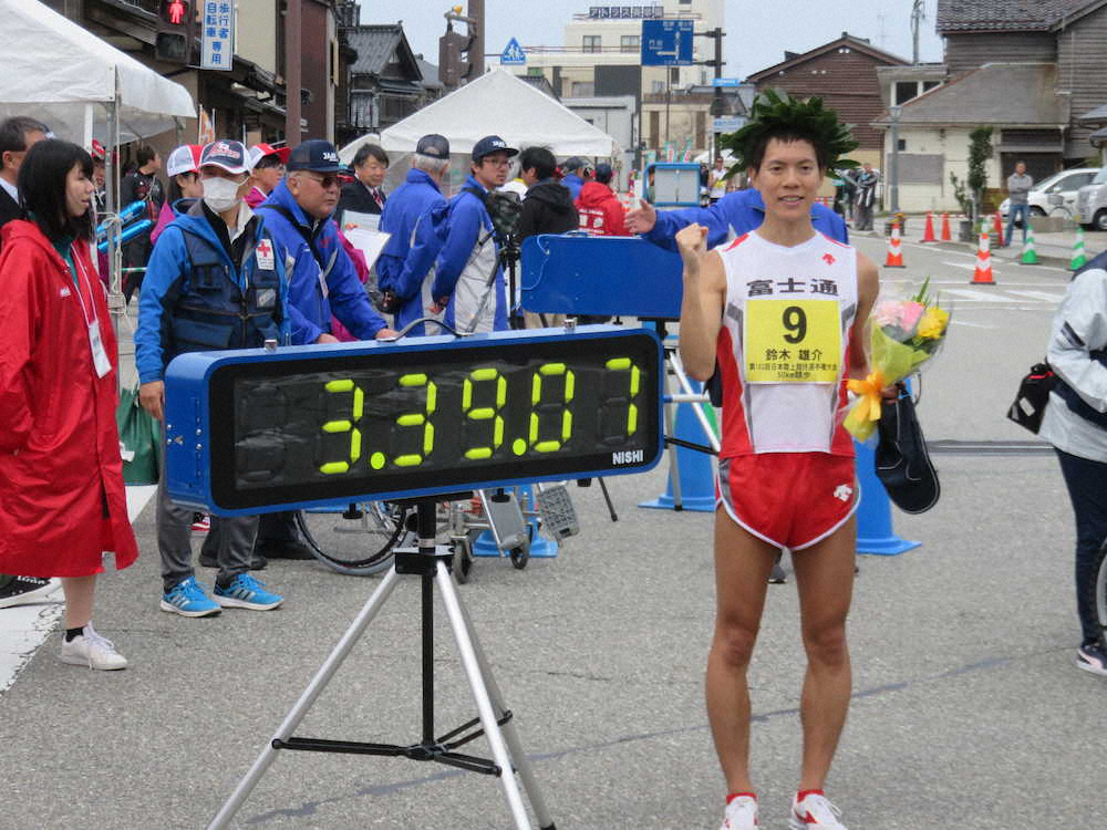 50キロ競歩の日本新記録をマークした鈴木雄介は速報計時版の前でポーズ（撮影・中出健太郎）