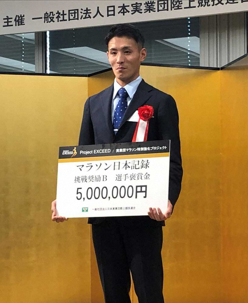 日本実業団陸上競技連合の表彰式に出席した服部。褒賞金500万円のボードを手に笑顔を見せる