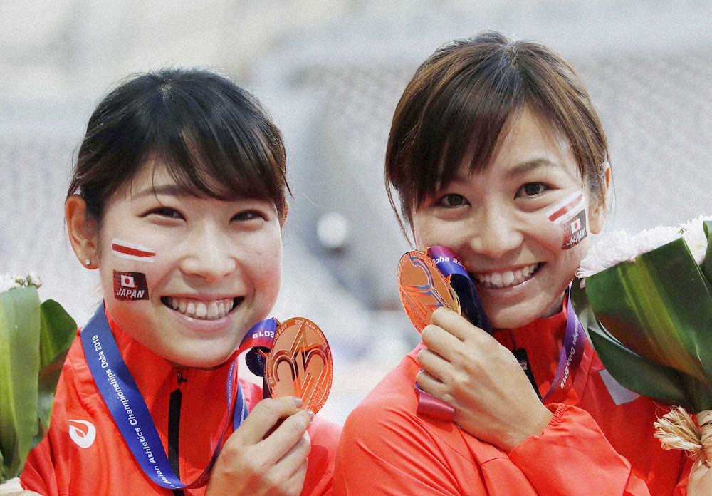 女子100メートル障害で金メダルを獲得し、笑顔でポーズをとる木村文子（右）。左は3位の青木益未
