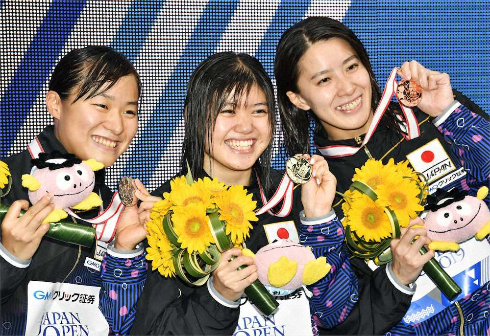 女子200メートルバタフライで優勝し笑顔の長谷川涼香。左は2位の牧野紘子、右は3位の大橋悠依