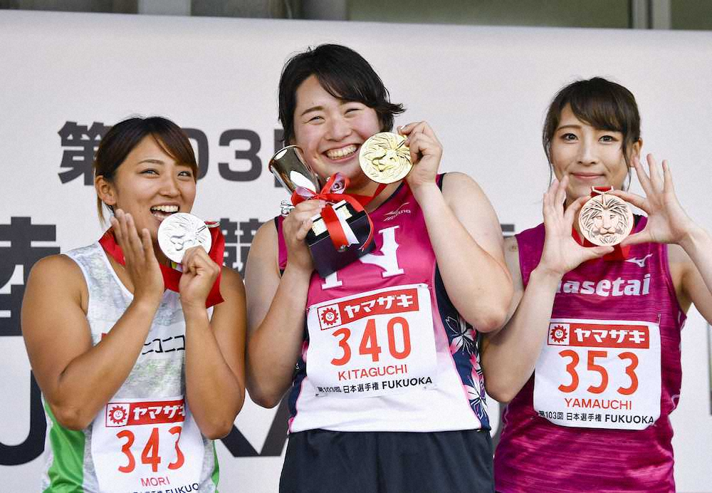 女子やり投げで優勝し、メダルを手に笑顔を見せる北口榛花。左は2位の森友佳、右は3位の山内愛