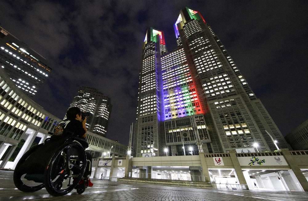 東京五輪の開幕まで1年となり、五輪カラーにライトアップされた東京都庁舎＝24日夜