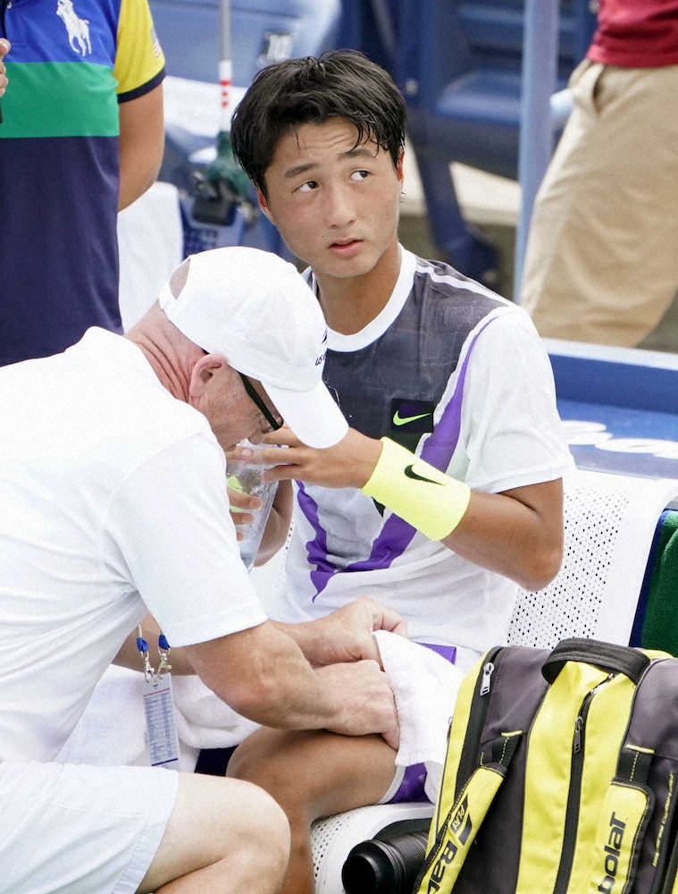 男子シングルス2回戦の試合中、左脚の治療を受ける望月慎太郎（共同）