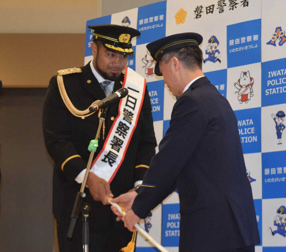 磐田警察署の鈴木宏哉署長（右）から指揮棒を渡される一日警察署長のヘルウヴェ