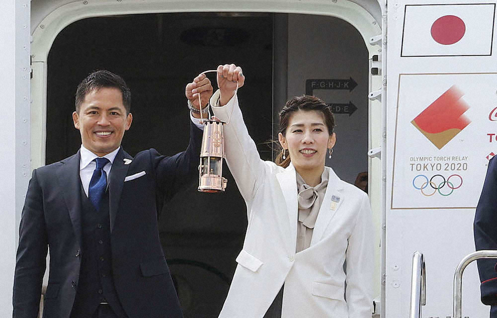20日、ギリシャから特別輸送機で到着した東京五輪の聖火を掲げる野村忠宏さん（左）と吉田沙保里さん