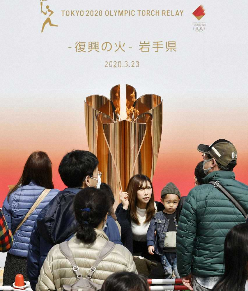 「復興の火」としてともされた東京五輪の聖火の前で記念撮影する来場者