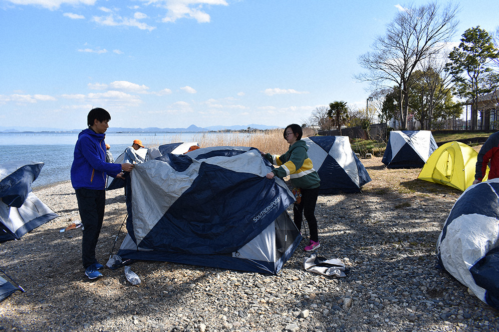 1人用テントを設置する北田雄夫氏と参加者