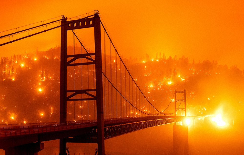 9日、橋の後方の丘で燃え広がる炎。米カルフォルニア州（AP）