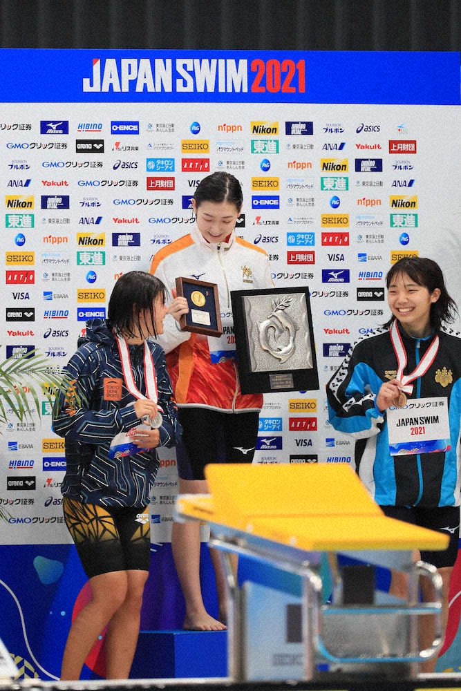 女子100メートルバタフライ表彰、表彰台でメダルを見つめる池江（中央）＝撮影・会津　智海