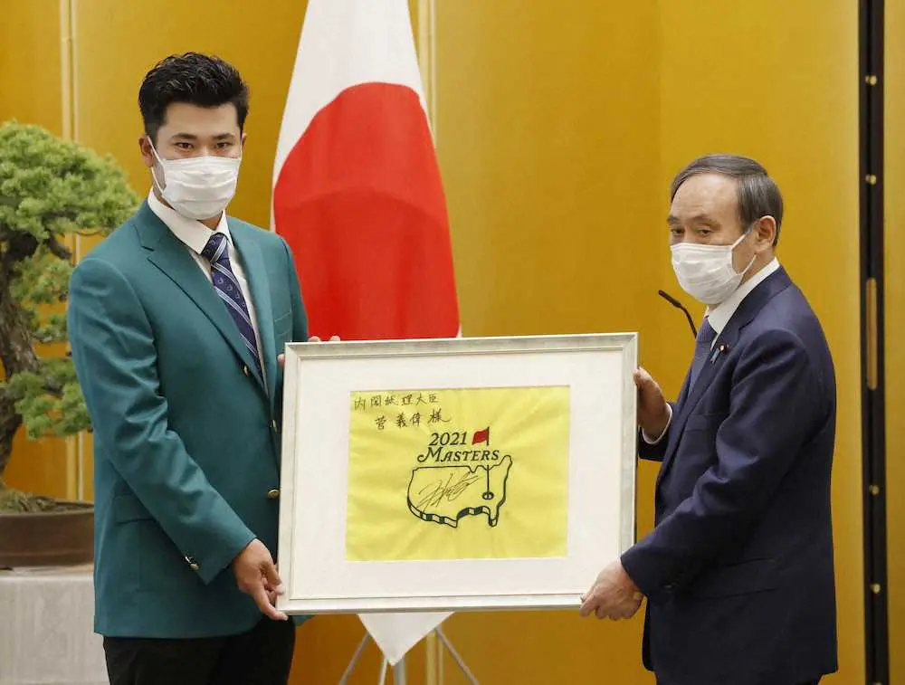 菅首相（右）に記念品を手渡す松山英樹