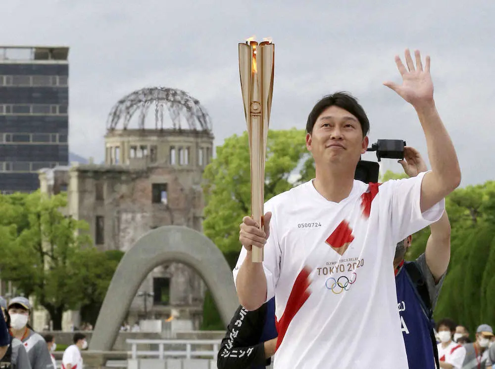 広島市の平和記念公園で聖火のトーチを掲げる新井貴浩さん