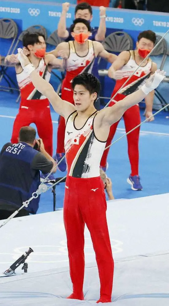 体操男子団体総合決勝　最終種目の鉄棒で着地を決めた橋本と喜ぶ日本チーム