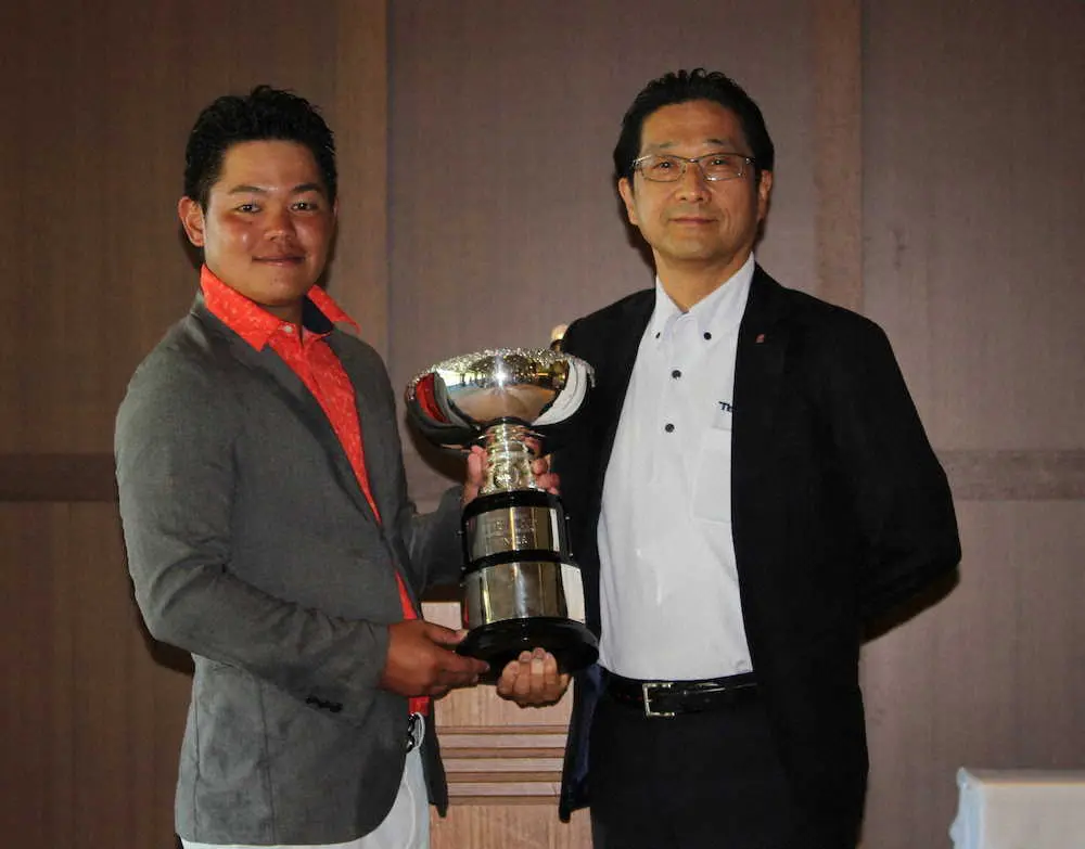 プレーオフを制して大会初優勝の照屋（左）は永田大会名誉会長からカップを贈られ笑顔